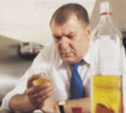 Depressed man looking at drink with bottle